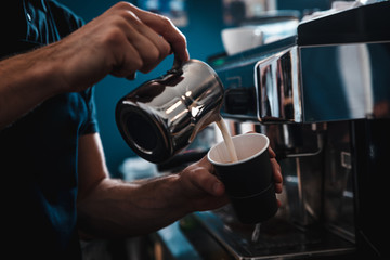 Close up of barista hands preparing cappuccino to go in cafe shop.