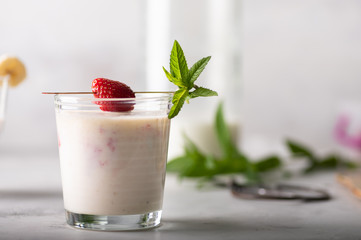 Banana and strawberry milkshake with mint leaves garnish. Light high key image, healthy and delicious breakfast concept