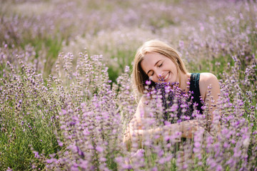 Beautiful girl in purple lavender field. Beautiful woman walk on the lavender field. Girl collect lavender. Enjoy the floral glade, summer nature. Natural cosmetics and eco makeup concept.
