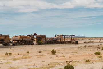 Train Cemetry Bolivia Salt Flats. Bolivian salty desert and blue sky background. Shot in Salar de Uyuni. Rusted, waste, abandoned, locomotive graveyard, railroad concepts. Tourist attraction