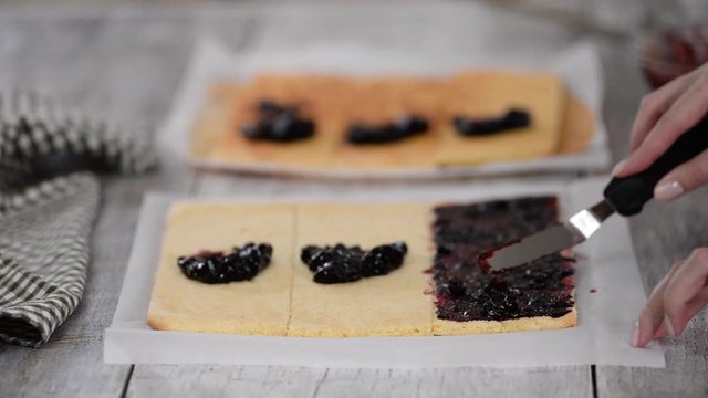 Girl spreading jam on a flat sheet of cake to make a cake with vertical layers at home.