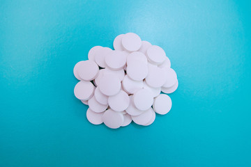 White pills on blue background close up, horizontal, copy space, medical concept.