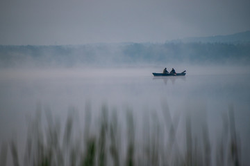 Rybacy wiosłują łódką podczas wchodu słońca w Świerklańcu.