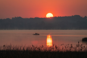 Wędkarze płyną przez jezioro w świerklańcu podczas wschodu słońca.