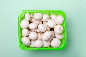 Closeup of fresh and natural white champignon mushrooms in the green box
