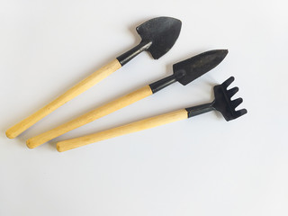 Garden tools: rake and shovels. Separately on a white background. Miniature gardening tools with a wooden handle on a white background. The concept of soda farming and agriculture. Place for text. 