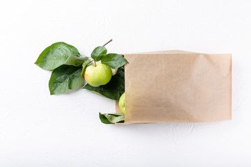 Ripe green apples with leaves in paper bag on white background. Top view, copy space, close-up.