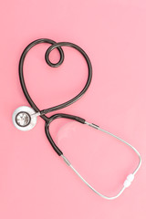 Obraz na płótnie Canvas Stethoscope in the shape of heart on pink background Medicine concept, symbolic association with love, cardiology
