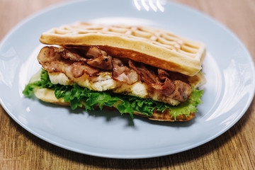 tasty Belgium waffle with lettuce, meat, egg and vegetables served of pretty blue plate