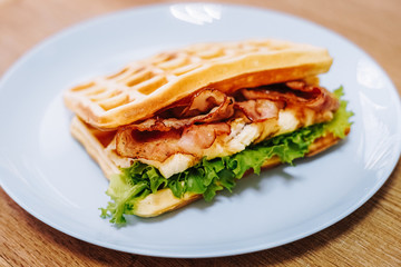 tasty Belgium waffle with lettuce, meat, egg and vegetables served of pretty blue plate