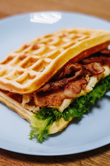 tasty Belgium waffle with lettuce, meat, egg and vegetables served of pretty blue plate