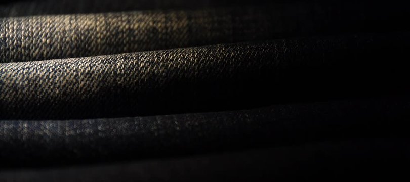 A close up texture background of blue jeans fabric empty space macro shallow focus with moving light
