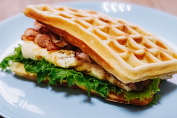 tasty Belgium waffle with lettuce, meat, egg and vegetables served of pretty blue plate