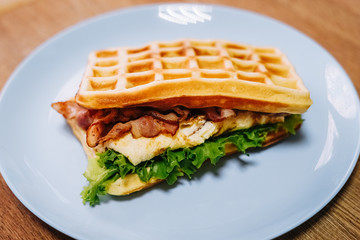 tasty Belgium waffle with lettuce, meat, egg and vegetables served of pretty blue plate