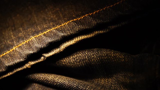 A close up texture background of blue jeans fabric empty space macro shallow focus with moving light
