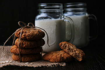 homemade oatmeal cookies tied with string on natural linen napkin with lace, next to two cans of...
