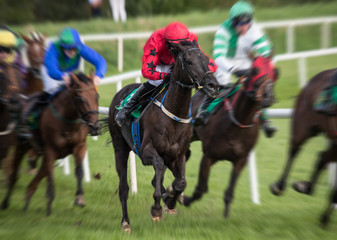 Motion blur speed effect on race horses and jockeys galloping on the race track