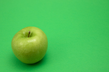 One granny smith apple on green background