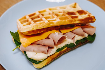 tasty Belgium waffle with lettuce, meat, egg and vegetables served of pretty blue plate