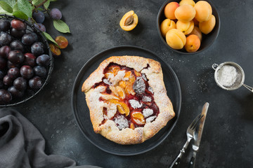 Pie galette with apricot and plum on black. View from above.