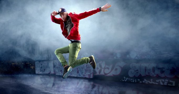 Male street dancer in a jump with a graffity wall behind the fog on a backgroung.