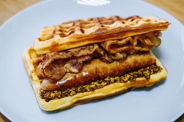 tasty Belgium waffle with lettuce, meat, egg and vegetables served of pretty blue plate
