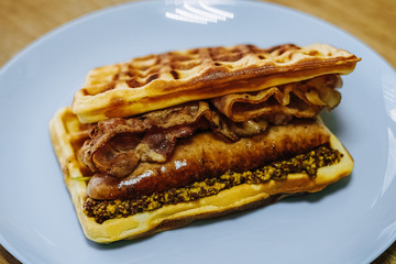 tasty Belgium waffle with lettuce, meat, egg and vegetables served of pretty blue plate
