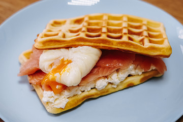 tasty Belgium waffle with lettuce, meat, egg and vegetables served of pretty blue plate