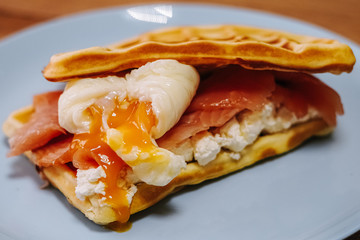 tasty Belgium waffle with lettuce, meat, egg and vegetables served of pretty blue plate