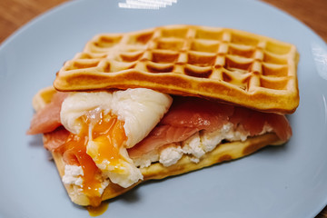 tasty Belgium waffle with lettuce, meat, egg and vegetables served of pretty blue plate