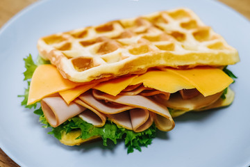 tasty Belgium waffle with lettuce, meat, egg and vegetables served of pretty blue plate