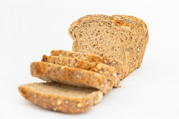 Cut rye loaf baked at home. Sliced delicious cereal pieces laying together isolated on white background. Studio shot. Selective focus. Side view. Homemade bakery and nutrition concept