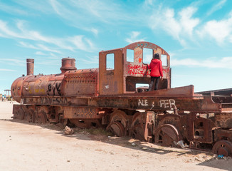 Tourist, Train Cemetry Bolivia Salt Flats. Bolivian salty desert and blue sky background. Shot in Salar de Uyuni. Rusted, waste, abandoned, locomotive graveyard, railroad concepts. Tourist attraction