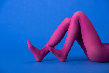 cropped view of model in bright purple tights posing on blue