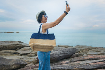 Female travelers take a picture with a smartphone in a seaside tourist spot