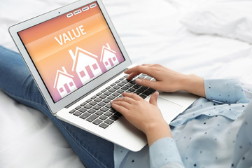 Property value concept. Woman working with laptop on bed, closeup