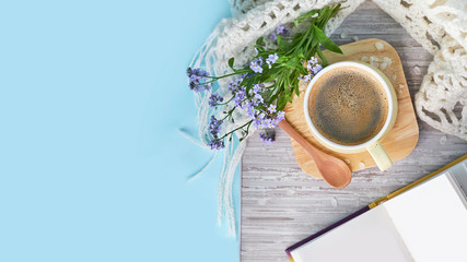 Cozy home still life: cup of hot coffee, spring flowers and opened book with warm plaid. Springtime concept, free copy space. close up top view