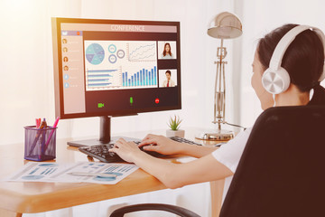 Back view of business woman talking to her colleagues about plan in video conference.