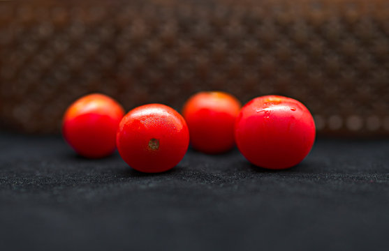 Tomates cherry sobre una mesa negra y una celosía de madera