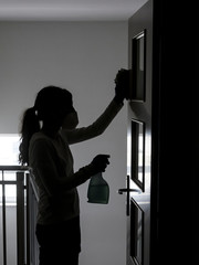 caucasian woman cleaning and disinfecting a door frame with a cloth and spray in Spain