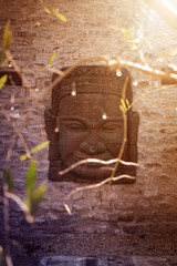 Fototapeta na wymiar Buddha face made of stone illuminated by sun rays at sunset