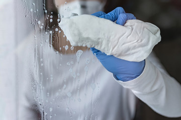 caucasian woman cleaning and disinfecting a glass with a cloth and spray in Spain