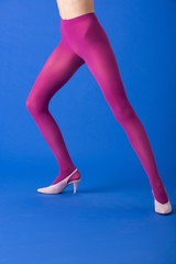 cropped view of woman in bright purple tights and heels standing on blue