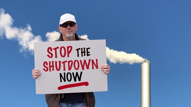 American worker with cap standing in front of industrial smoking chimney
with board sign saying Stop the Shutdown Now. Corona Covid-19 lockdown protest. Collage image with copy space.