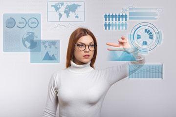 Serious woman working in virtual reality. Concentrated young woman in eyeglasses showing fingers and touching virtual global infographics. VR concept