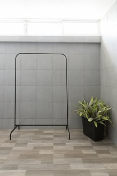 front view of empty black metal clothes drying rack or clothesline with stainless steel rail and plant in washing room