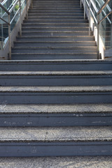 front view of outdoor staircase to pedestrian walkway with metal railing and glass fence at train station, selective focus.