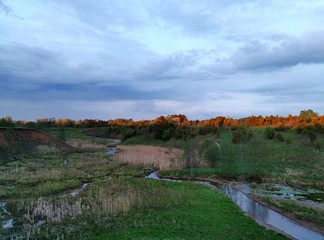 evening sky over a green marshland and a small river