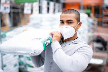 Ein Mann kauft zur Zeit des Coronavirus neues Material in einem Baumarkt ein, er trägt eine Maske - obrazy, fototapety, plakaty