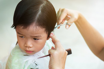 The little boy got his hair cut at home by his parents. In a situation that everyone must be aware of the real germs, can not go to the barber shop.